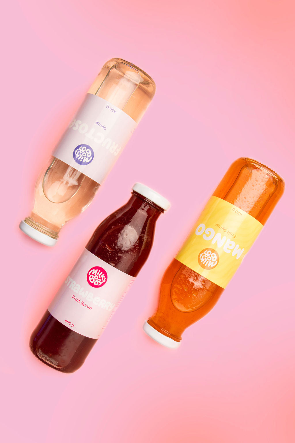 Three bottles, one fructose, one strawberry syrup, and one bottle of mango syrup